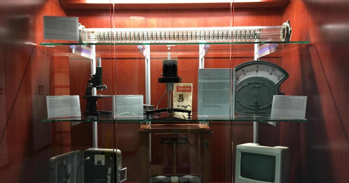 NJIT Distributed Technology Museum’s first 7-piece exhibit displayed in Fenster Hall (Top Shelf: York-Scheibel Column; Middle Shelf, Left: 1947 Bausch & Lomb optical microscope; Middle Shelf, Center: Brookefield Viscometer; Middle Shelf, Right: Weston Sta